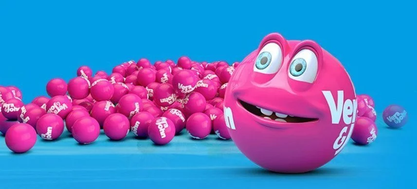 Blå bakgrund. En hög av rosa bingobollar syns på bilden. Längst fram står en rosa bingokula med ett mänskligt ansikte. 