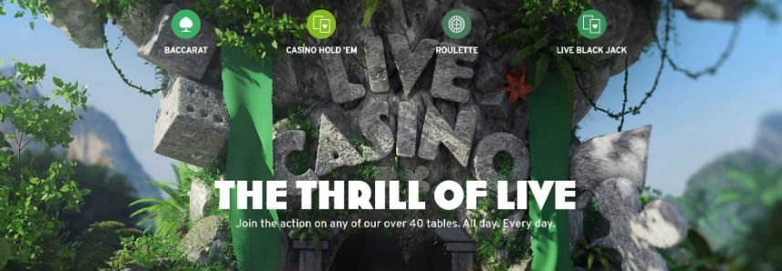 Bilden visar en djungel där ett stort träd(?) har stenar formade som tärningar hängandes och även stenar som formar ordet Live Casino. Under live casino står det "The thrill of live. Join the action on any of our over 30 tables. All day. Every day." Över ser vi länkar till Baccarat, Casino hold'em, Roulette och Live black jack.